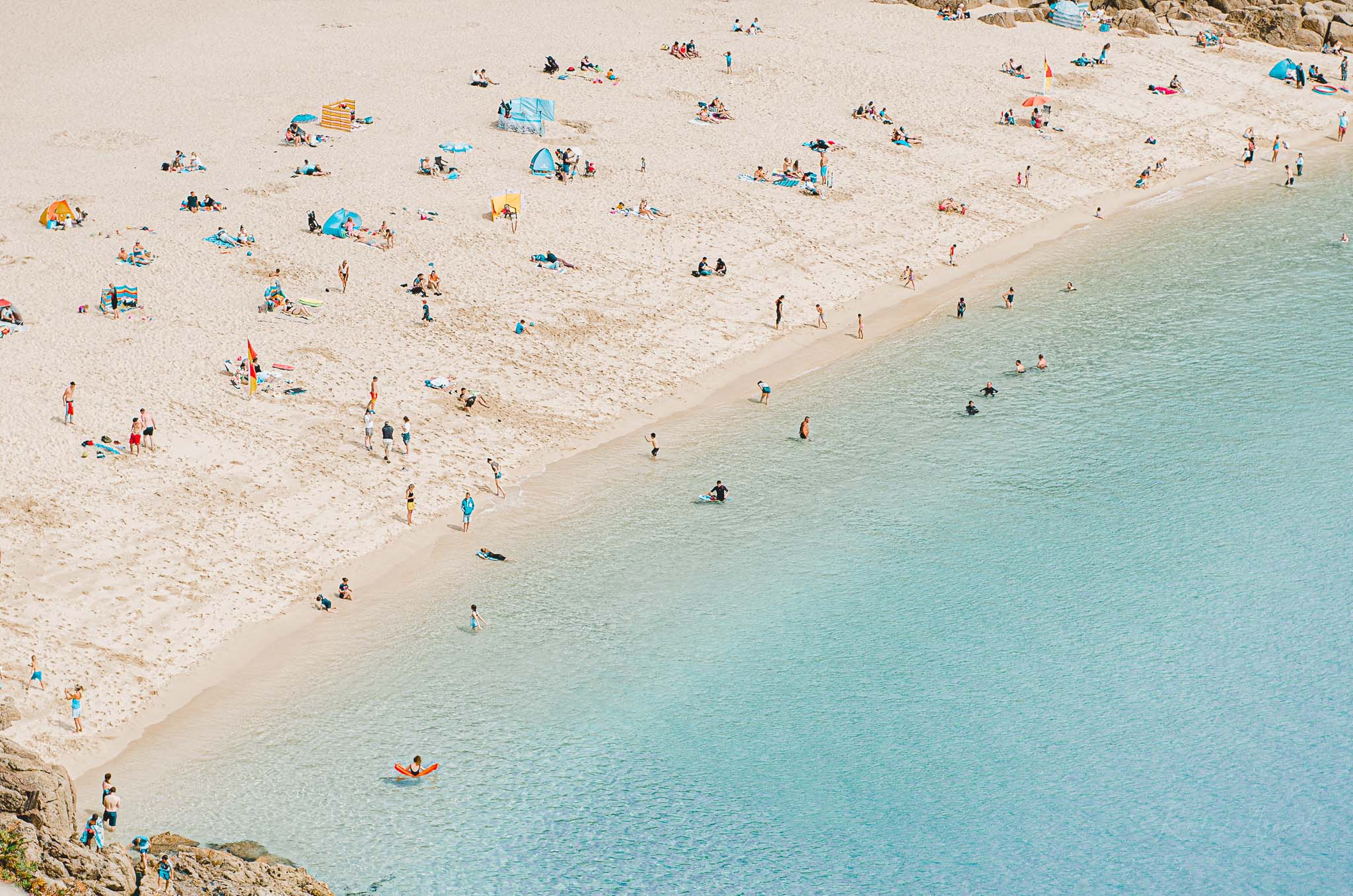 An above view of this small hidden beach with people enjoying the beach and blue sea