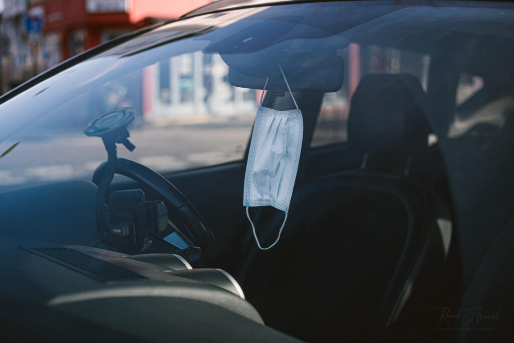 A parking car with a mask hanging from its mirror