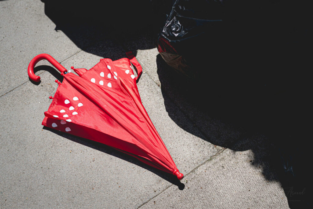 Left behind red kids umbrella on the side of the road